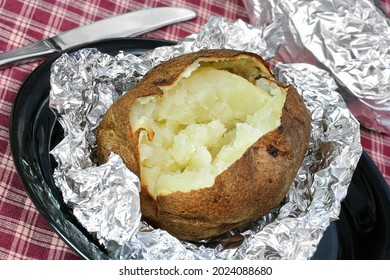 One Fresh Baked Potato, Open On Aluminum Foil.  No Toppings, Ready For Yours.