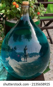 A One Gallon Glass Bottle Full Of Blue Liquid Outside Of A Craft Shop In The KIONI Port, ITHACA, Ionian Islands, Greece In The Summer Sunny Day. Horizontal.