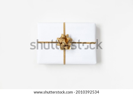 One gift box in white wrapping paper with gold rope on white table. Isolated wrapped gift mock up.