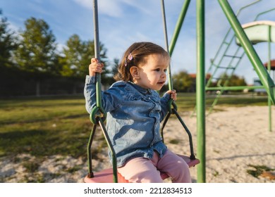 One Girl Small Caucasian Child Female Toddler 18 Months Old Having Fun In Park On The Swing Swinging Alone In Day Childhood And Growing Up Concept Copy Space