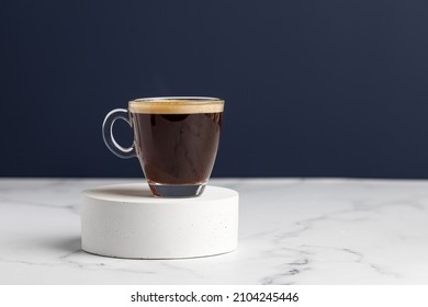 One glass coffee cup with espresso in morning on podium and white marble background. Aroma, ristretto. Mug of coffee. Blue wall