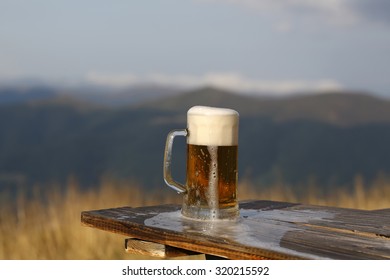 One glass mug with lager or porter tasty frothy beer on wooden table top sunny day outdoor on natural with mountain hills and yellow dry grass background, horizontal picture - Powered by Shutterstock