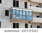 One glazed balcony in an unfinished block high-rise building.
