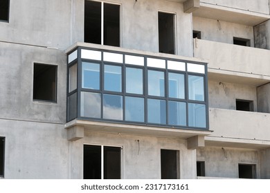 One glazed balcony in an unfinished block high-rise building.