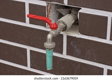 One Gray Metal Water Faucet With A Red Handle In A Brown Brick Wall Outdoors