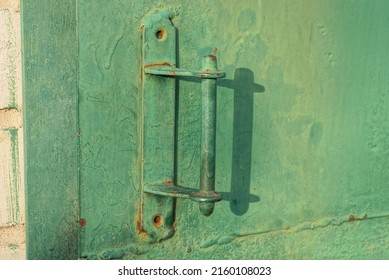 One Green Metal Doorknob On A  Iron Dirty Door And A Wall On The Street