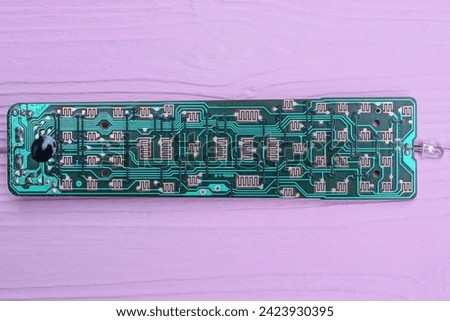 one green old long plastic microcircuit with lead soldering lies on a pink table