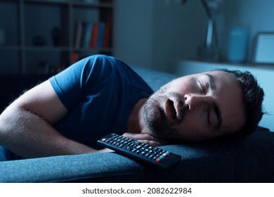 One Guy Sleeping On The Sofa At Night Watching Tv