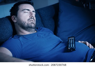 One Guy Sleeping On The Sofa At Night Watching Tv