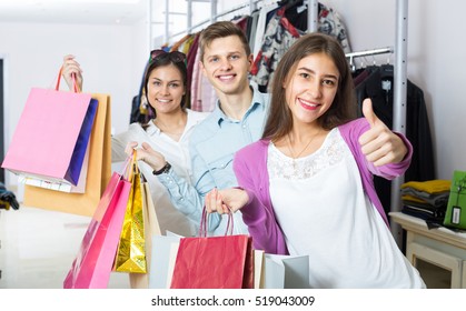 One Guy And Two Girls Holding Bags With Clothes In Apparel Store