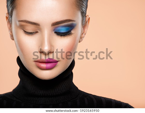 One half face of a beautiful white woman with \
bright makeup and the other is natural. Woman portrait with a deep\
blue eye makeup of one eye. Natural and  vivid make-up on a female\
face. Fashion style