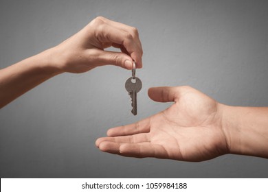 One hand giving key to another on isolated background. Process of buying renting selling. Agreement between two people for sales, and purchase.