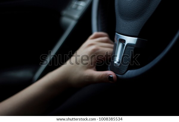 One hand holding a steering\
wheel