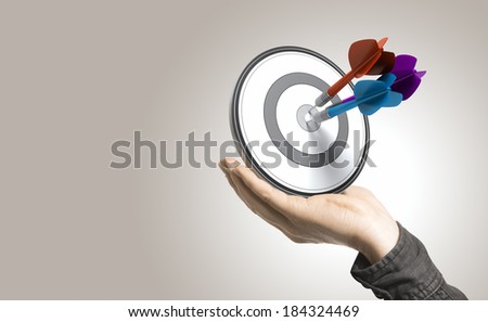 One hand holding a target with three darts hitting the center, beige background. Illustration of control and effective business solutions.