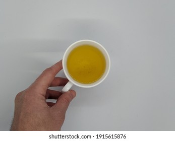 One Hand Holds A Cup Of Tea. Male Hand Holding A Cup Of Tea On A White Background Top View