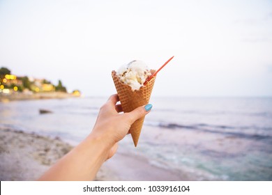 one hand holds tasty ice cream on a summer beach.