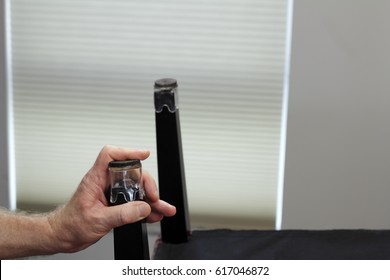 One Hand Installing One Clear Plastic And Felt Chair Floor Protector. Male Hand Placing A Chair Bottom Floor Protector On Ta Bottom Of A Dining Room Chair