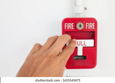 One hand pulling fire alarm on the wall.Fire alarm switch