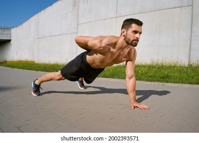 One hand pushup exercise. Athletic doing outdoor workout in the city
