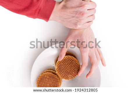 One hand trying to take a cookie from the plate other hand grabbed that arm to stop eating cookies. Decline. Prohibition. Ban. Risk. Dangerous. Healthcare. Reject. Prevent. Prevention. Stopping