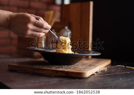 one hand use fork scoop spaghetti in black plate
