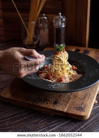 one hand use fork scoop spaghetti in black plate