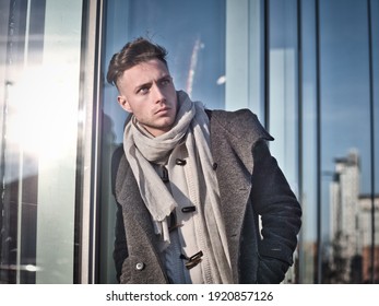 One Handsome Young Man In Urban Setting In Moden City, Standing, Wearing Black Coat And Scarf In Winter Day