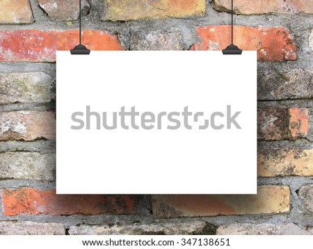 One hanged horizontal paper sheet frame with clips on weathered brick wall background