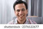 One happy 30s man look camera. Blue eyes gaze close up. Nice white teeth smile. Joy person have fun. Male face head shot. Brutal guy portrait inside home. Young adult model posing. Brunet dark hair.