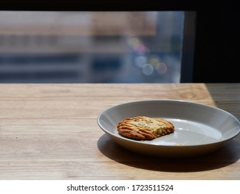 One Healthy Homemade Cereal Cookie That Was Left On A Gray Ceramic Plate On A Wooden Table On The Side Of The Window And Exposed To Sunlight.