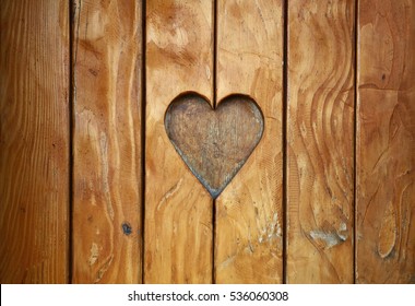 One heart shape, symbol of love and romance, wood carved cut in vintage old grunge natural brown wooden planks texture background, close up