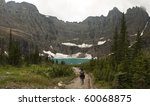 One hiker walking towards Iceberg Lake in Glacier National Park. The headwall of the valley is a perfect bowl formed by cliffs with hanging glaciers; the ice calves off to form icebergs in the lake.