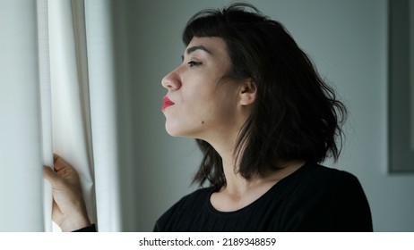 One Hispanic Woman Peeking Out Through Curtain Window