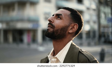 One Hopeful Arab man standing in street looking at sky in contemplation. Tracking shot, close-up face with happy expression
