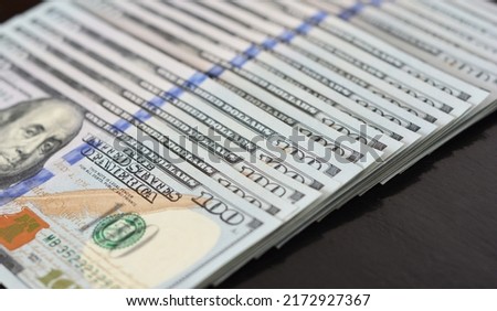 One hundred American dollars background. A row of one hundred dollar bills standing for US dollar exchange rate, money, earnings, or salary.