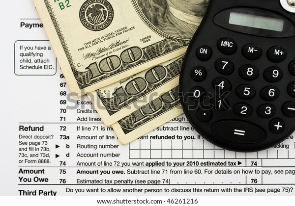 One hundred dollar bills and\
calculator sitting on tax papers, Calculating your tax\
refund