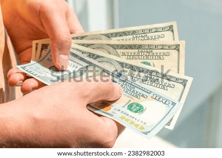 One hundred dollar bills in the hands of a white man. A man holds hundred dollar bills in his hands.