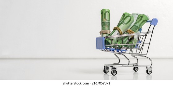 One Hundred Euro Banknotes Rolled Up In Rolls Lie In An Iron Trolley From A Supermarket. Banner.