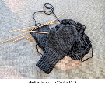 One knitted mitten and another mitten in progress, plus a ball of yarn