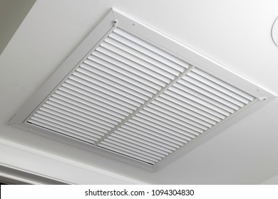 One Large White Painted Metal Furnace Air Vent Grill With Many Openings On A Ceiling Close-up. Square Outflow Air Filter Door Vent In A Modern Home Ceiling Up Close.