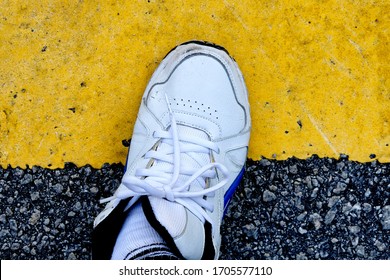 One Leg Or Foot Standing Halfway On A Road Yellow Line, Closeup Above Top View. Concept For Being Undecided, Impartial, Not Taking Sides, Sitting On The Fence Or Target Just Reached, Goal Achieved.