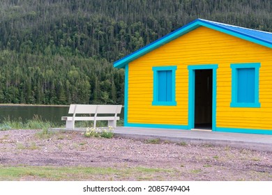 A One Level Seaside Colorful Yellow And Green Beach Cottage With A Blue Metal Roof. The Exterior Wall Is A Retro Color Cape Cod Siding. There's A Door Leading To A Washroom With A Concrete Patio. 