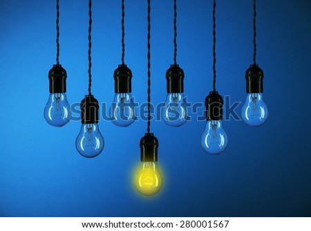 One light bulbs with glowing one isolated over blue background-leadership concept