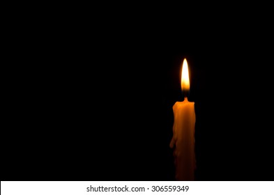 One Light Candle Burning Brightly In The Black Background