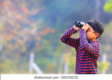 One Little Boy Use Binoculars Watching Bird In Nature With Blurry Background.