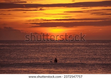One lone surfer out, as the sun peeks over the horizon. Photo was taken at sunrise at a local beach break in Miyazaki, Japan. 