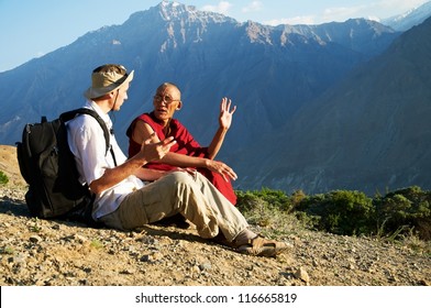 One male tourist and buddhist monk discussing in mountains
