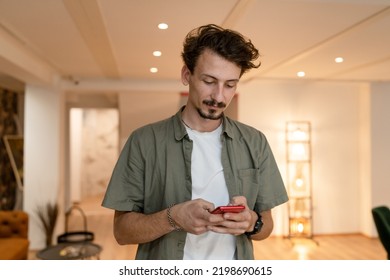 One Man Adult Caucasian Male With Haircut And Beard Mustaches Modern Person Standing Indoor At Restaurant Or Cafe Using Mobile Phone For Text Messages Communication Online Chat Or Browsing Internet