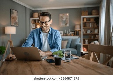 one man adult caucasian male with beard work on his laptop computer at home happy smile success freelance entrepreneur or remote work concept