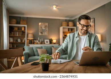 one man adult caucasian male with beard work on his laptop computer at home happy smile success freelance entrepreneur or remote work concept